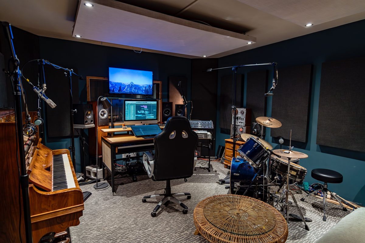 Field studio interior — piano, mics, drum kit, monitors